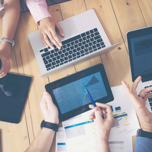 Young Business Team Brainstorming Meeting Room Process.Coworkers Startup Marketing Project.Creative People Making Great Work Decisions Wood Table.Tablet Laptop Graphs Diagram Screen.Blurred Background